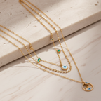 Gold necklaces with eye-shaped pendants on a light stone surface